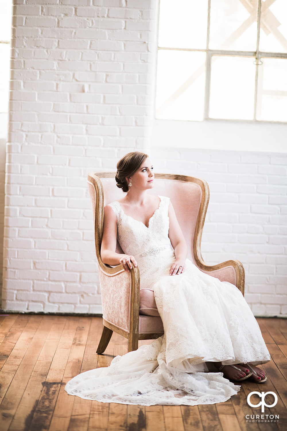 Bride sitting in a chair in window light.