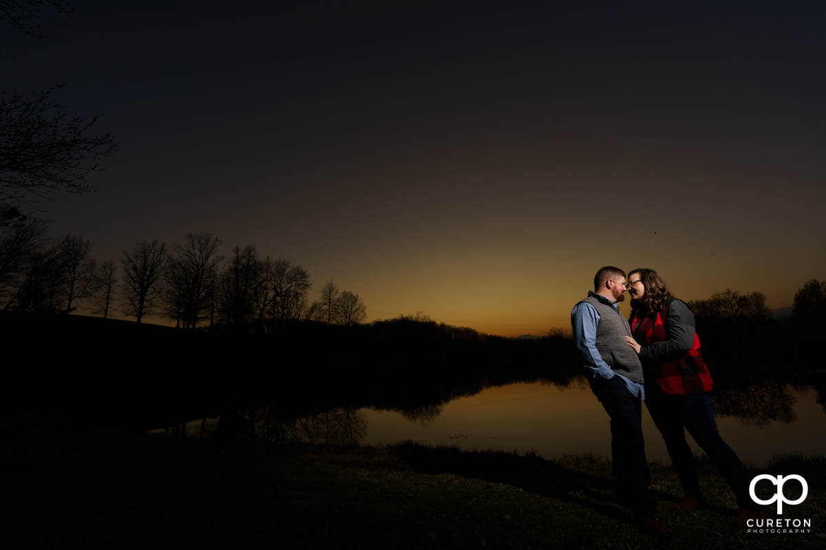 Engaged couple playing by the lake during a pre wedding South Wind Ranch engagement session in Travelers Rest,SC.