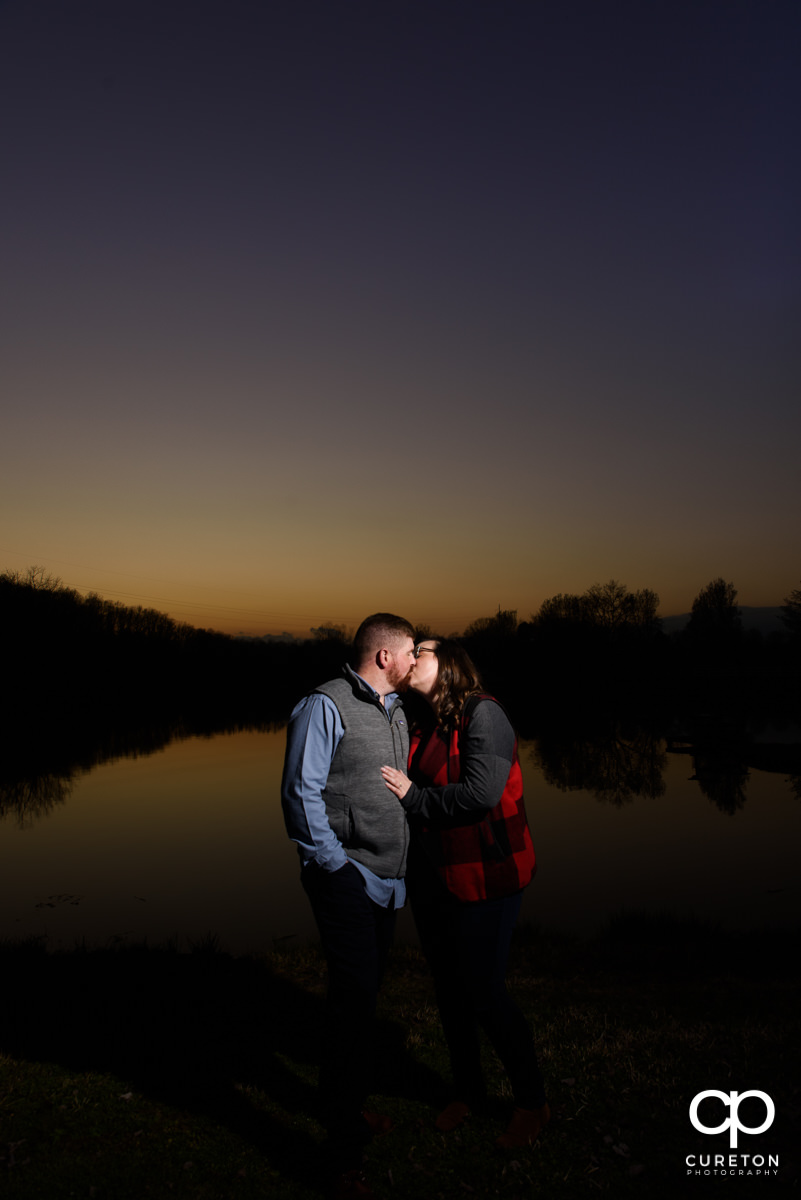 Engaged couple kissing at sunset at South Wind Ranch.