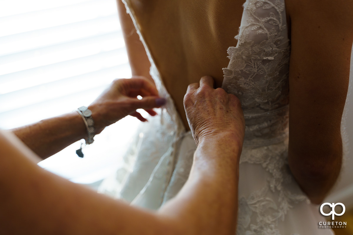 Bride's mom buttoning the back of her dress.