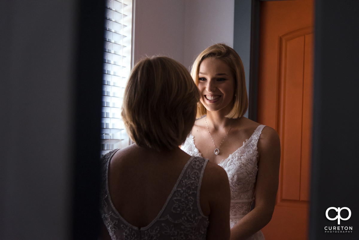 Bride smiling at her mom helping her get ready for the wedding.