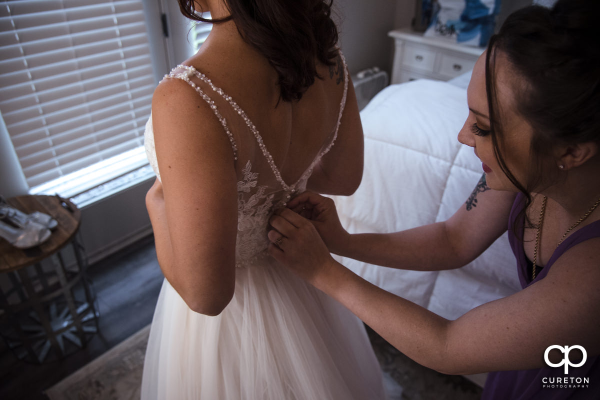 Bride buttoning dress.
