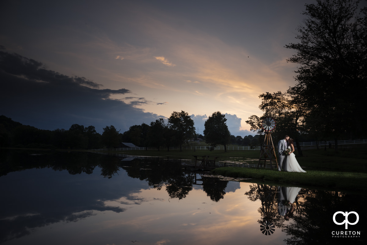 Groom kissing bride by a pond.