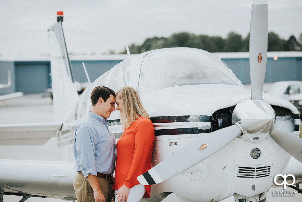 Engaged couple leaning on a plane during a Spartanburg Airport engagement session.