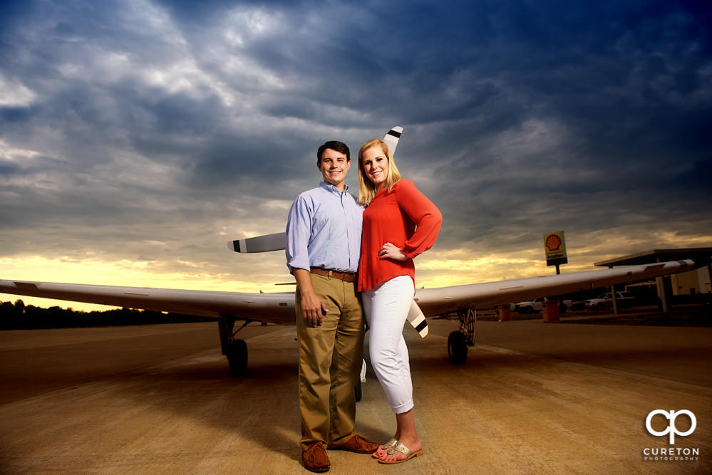 Future bride and groom standing in front of a plane during a Spartanburg Airport engagement session.