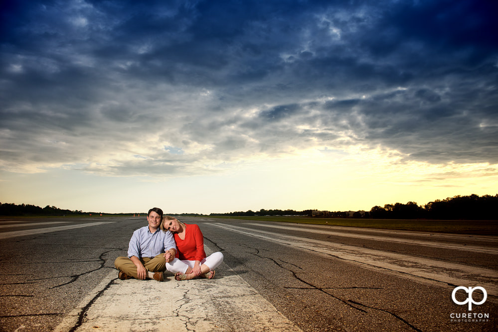 Bride and groom at sunset sitting on the runway during a Spartanburg Airport engagement session.