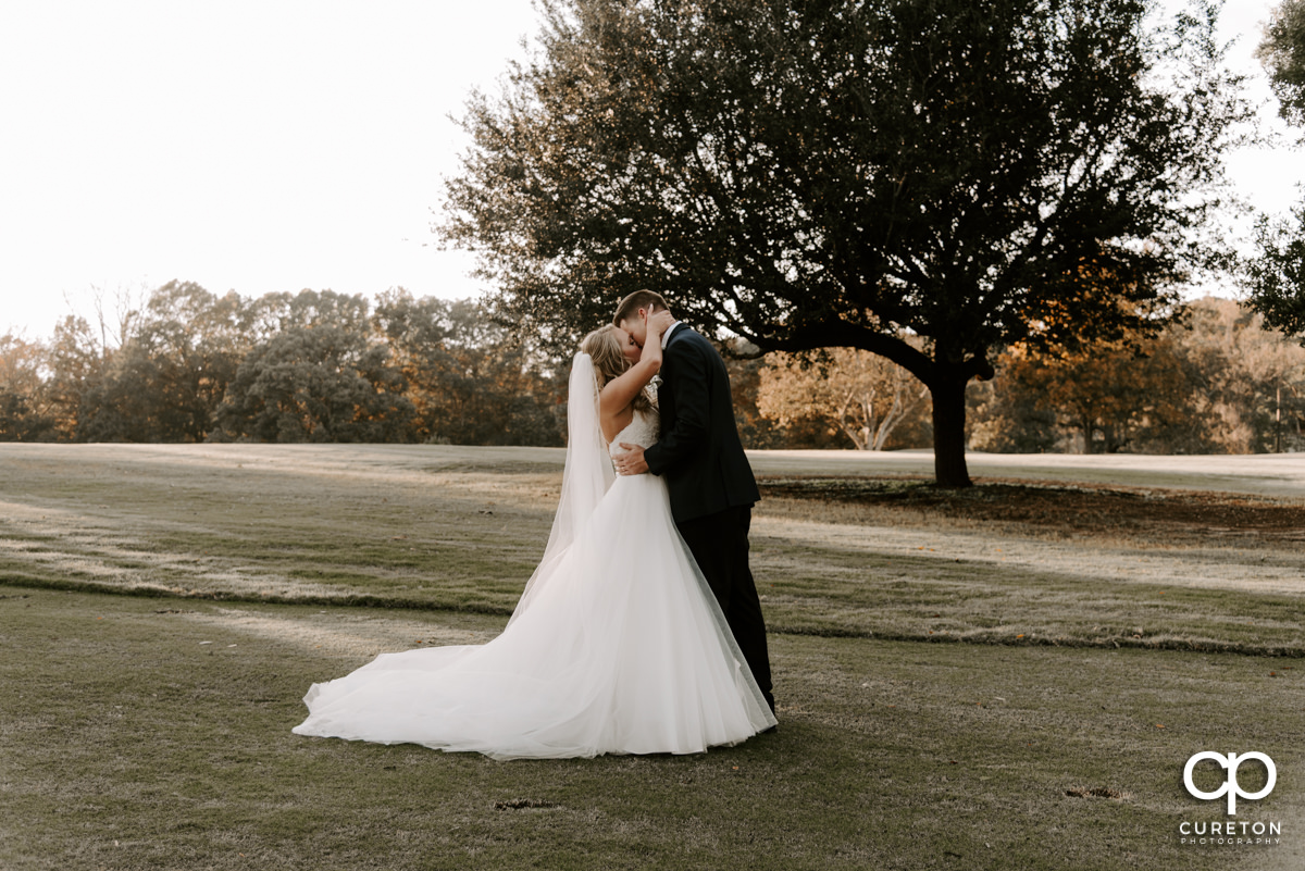 Bride and groom kissing on the golf course.