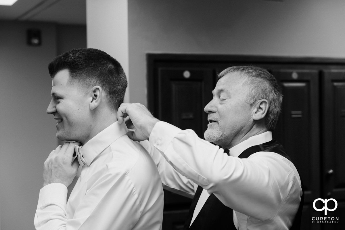 Groom's father helping him with his tie.