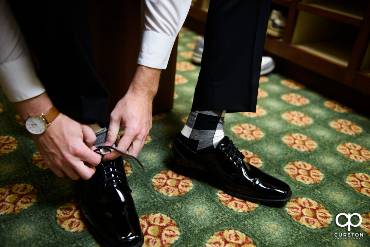 Groom tying his shoes on his wedding day.