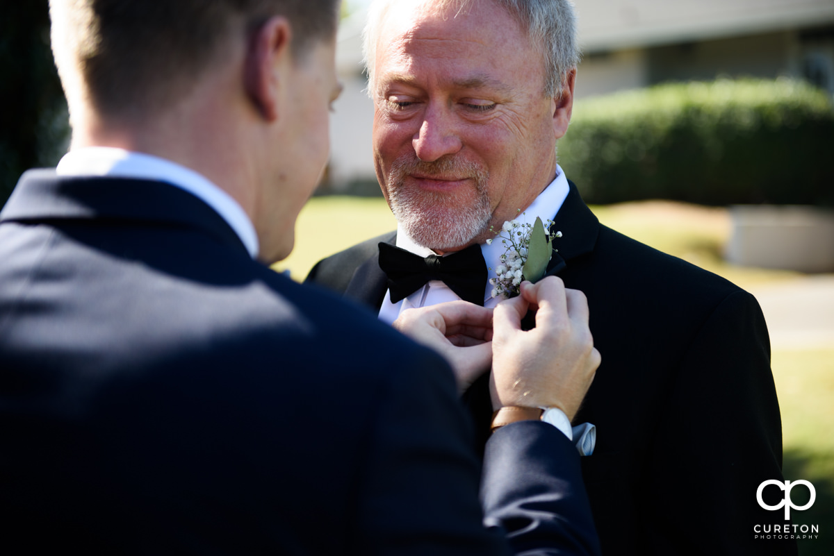 Groom helping his father pin his boutonniere.