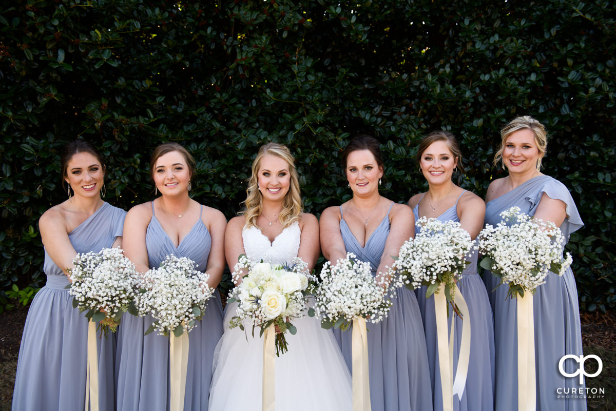 Bride and her bridesmaids showing off their flowers.
