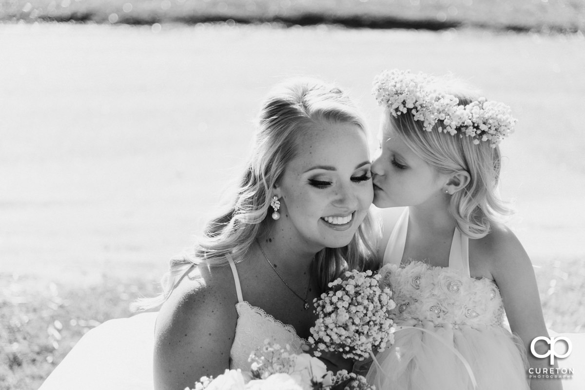 Flower girl kissing the bride on the cheek.