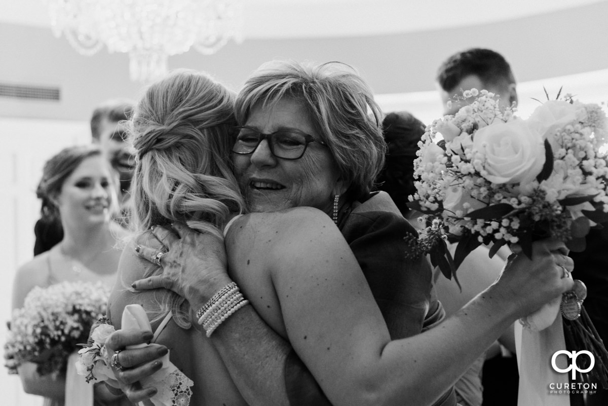 Groom's mother hugging his bride.