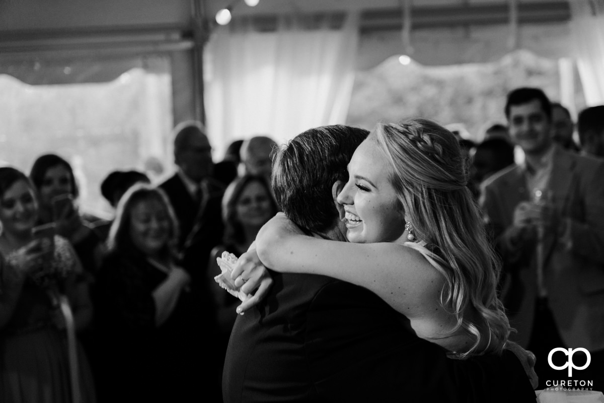 Bride hugging her father on the dance floor at the wedding reception.