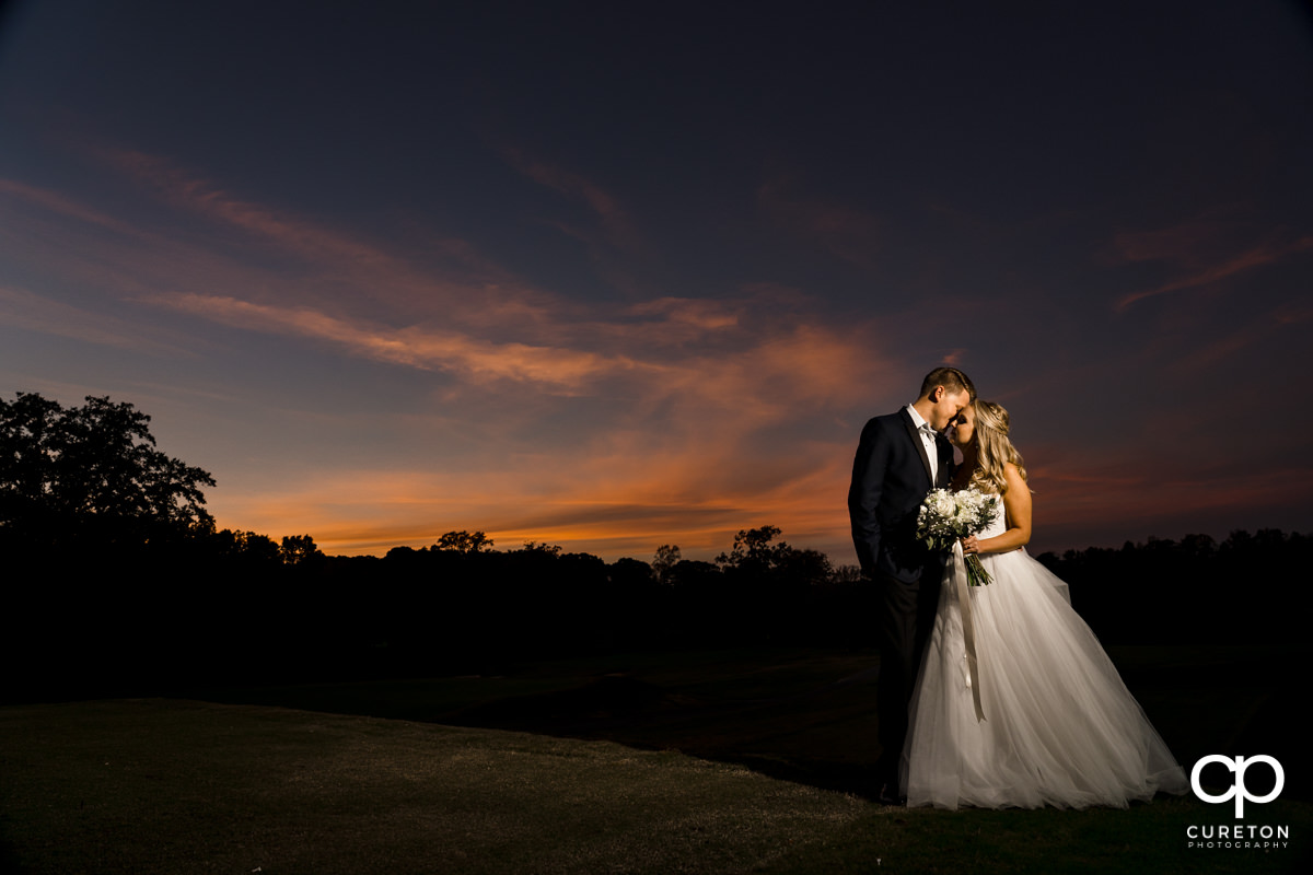 Bride and groom dancing on the golf course at Spartanburg Country Club at sunset during their wedding reception.