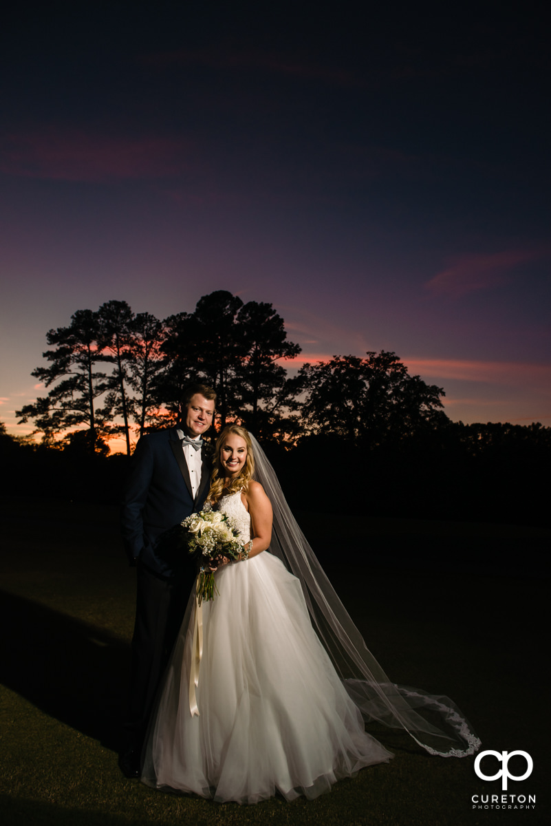 Bride and groom in front of a purple sky on their wedding day.