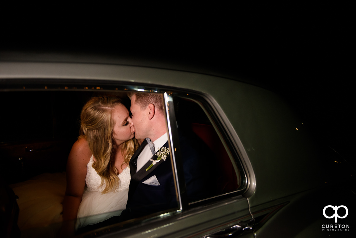 Bride and groom kissing in the getaway car.