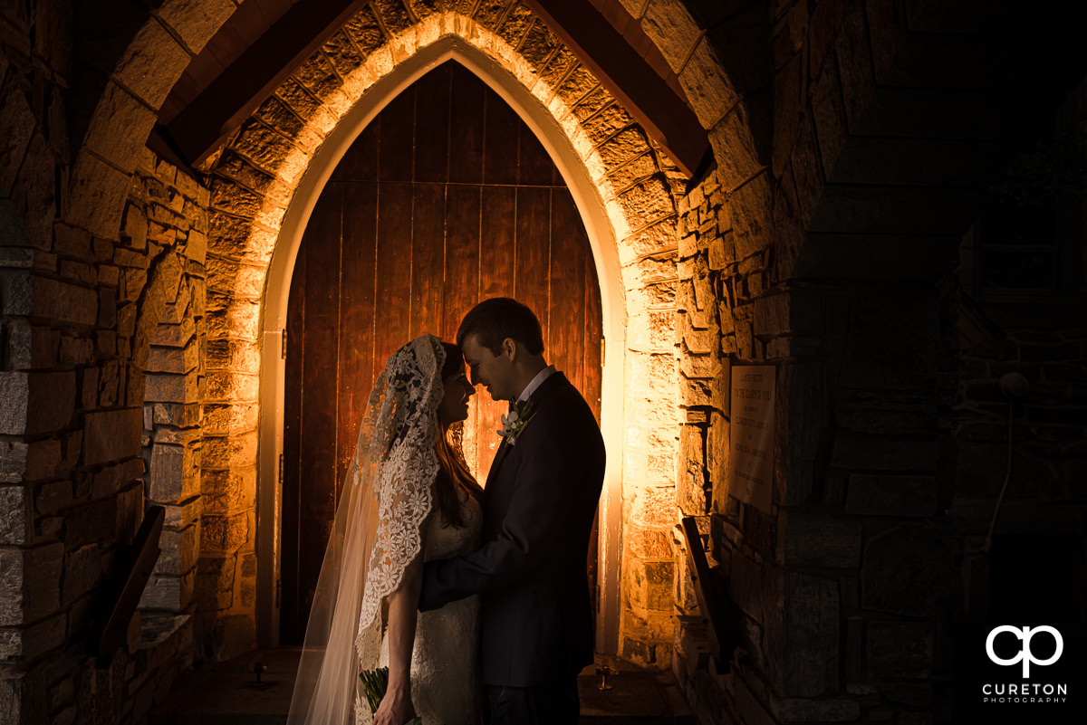 Bride and groom standing in a backlit arched doorway at the church of the advent after their Spartanburg wedding.