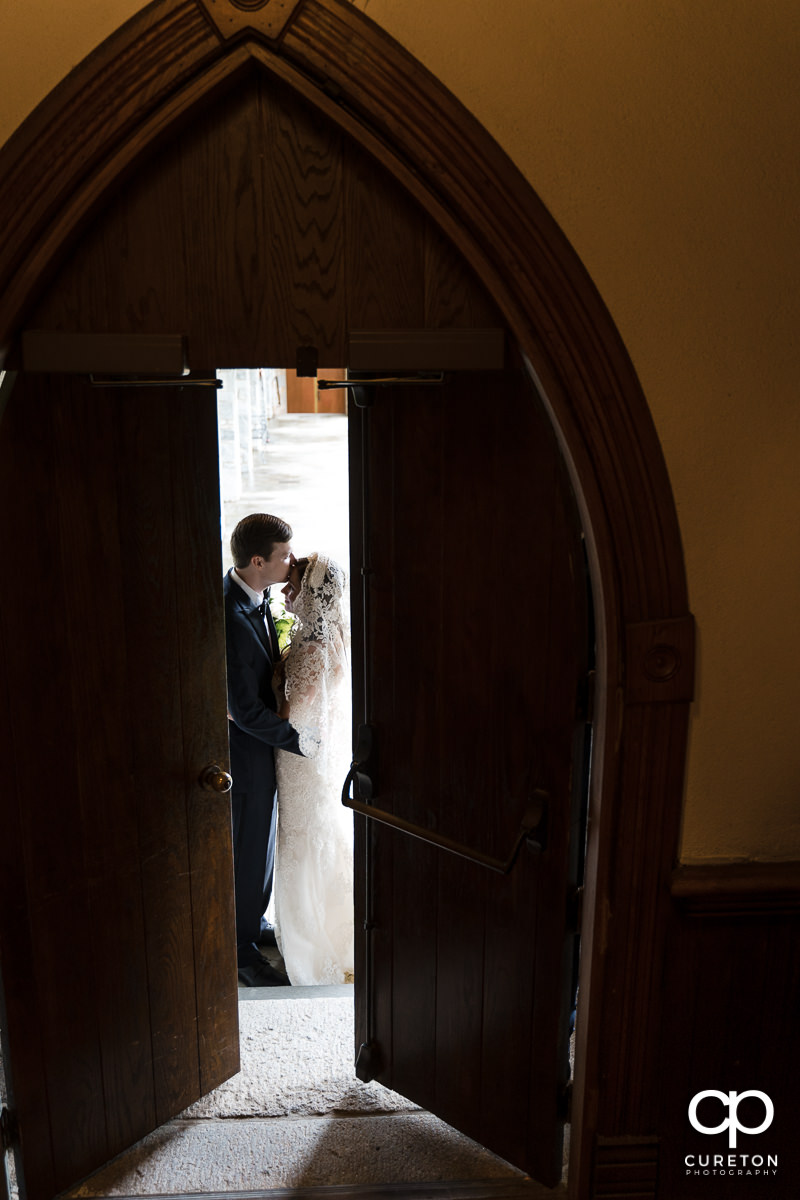 Bride and groom kissing behind opening doors at their wedding in Spartanburg.
