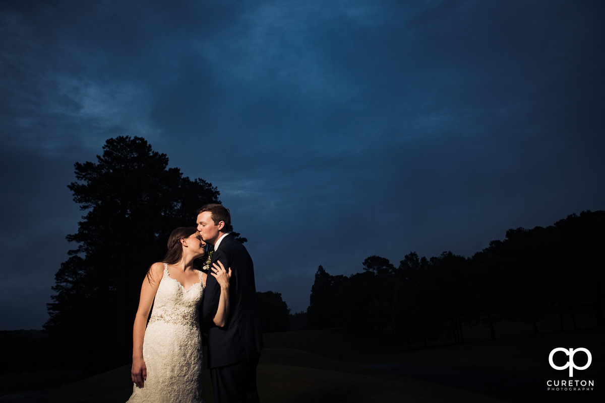Groom kissing his bride on the forehead at sunset on the golf course at their wedding reception at Spartanburg Country Club.
