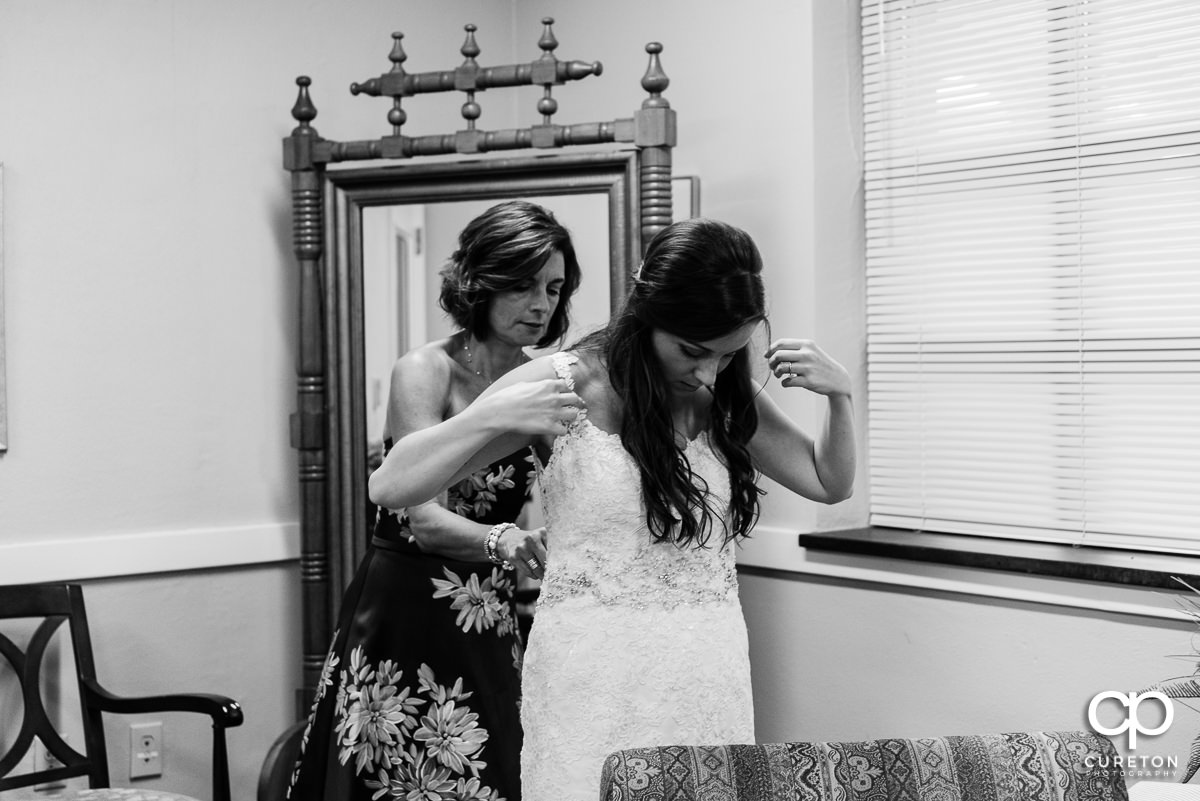 Bride being helped into her dress by her mother.