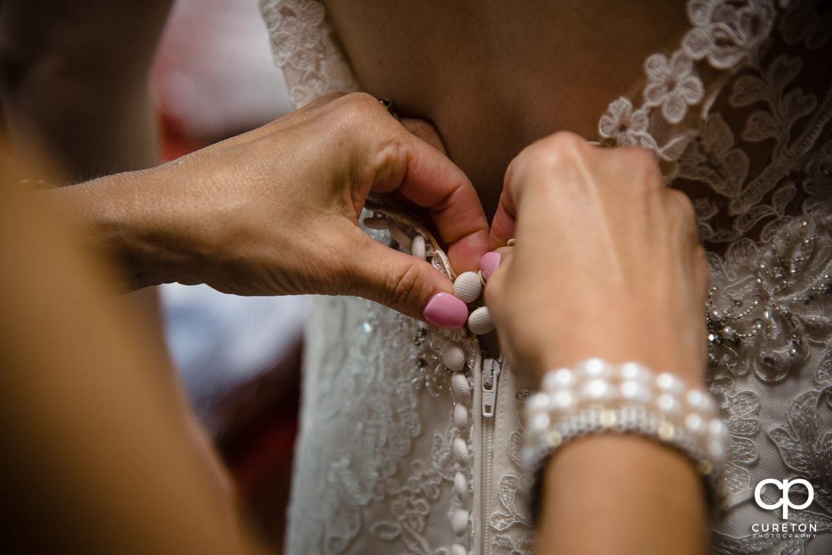 Bride's mom buttoning her dress.