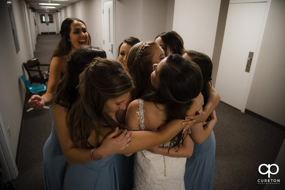 Bride being hugged by her bridesmaids.
