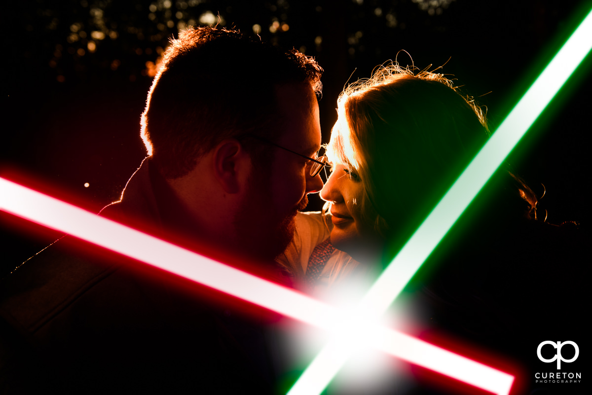 Bride and groom nose to nose with crossing lightsabers at their Star Wars engagement session.