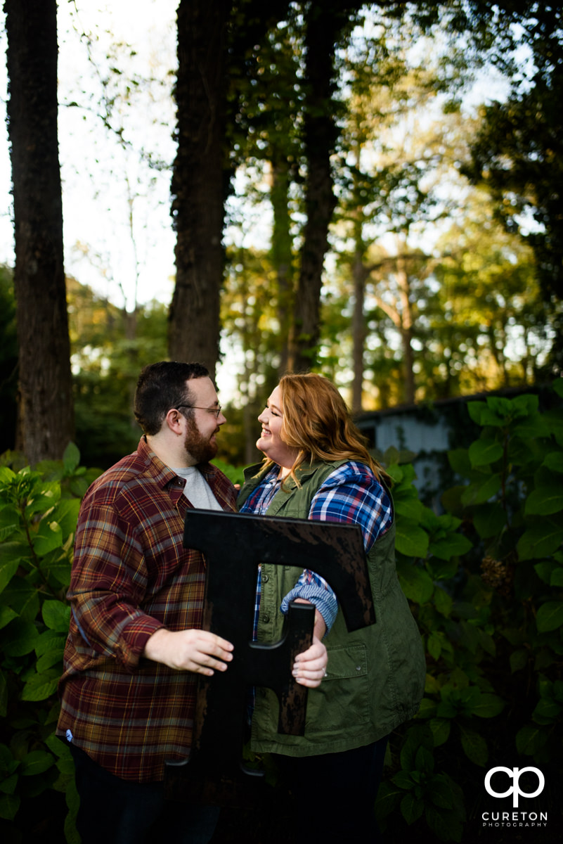 Engaged couple holding a wooden letter.