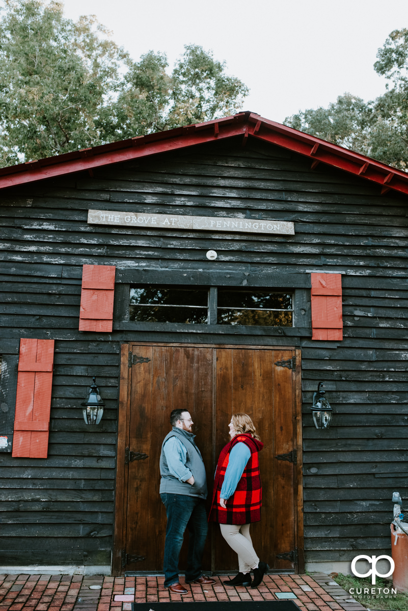 Bride and groom leaning on a rustic barn.