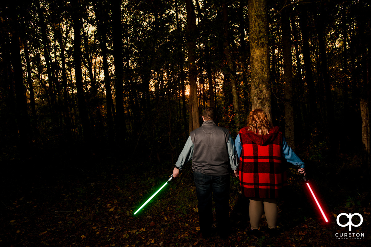 Engaged couple holding lightsabers at their Star Wars engagement session.