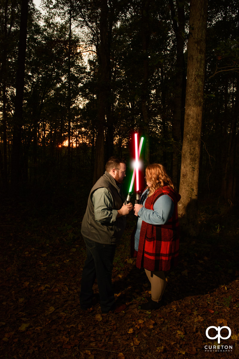 Engaged couple crossing lightsabers.