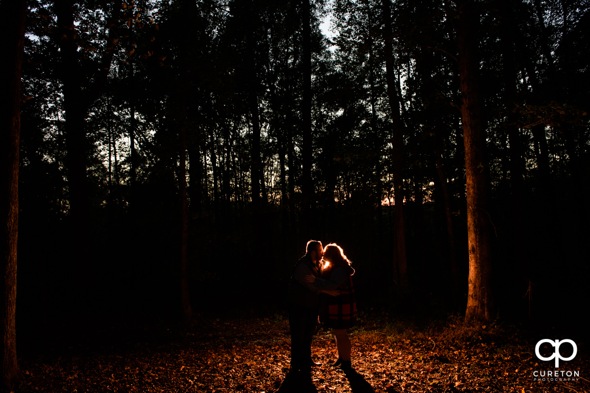 Engaged couple walking in the forest at sunset.