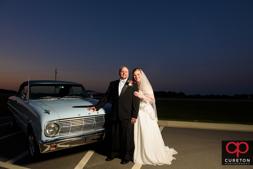 MArired couple posing with a ford falcon after their weddingin Sumter,SC.