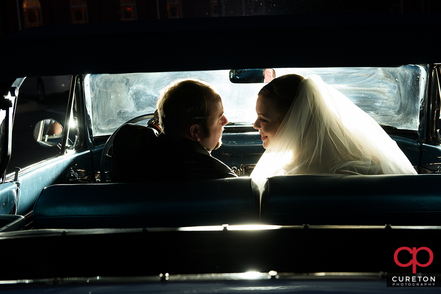 Epic backlit photo of a couple inside a vintage car.