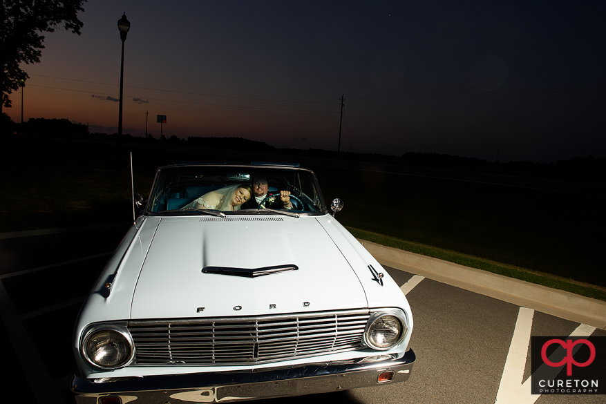 Bride and groom at sunset in a ford falcon vintage car after their wedding.