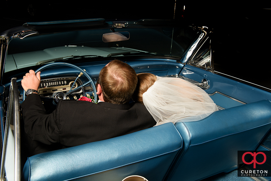 Bride and groom at sunset in a ford falcon vintage car after their wedding.