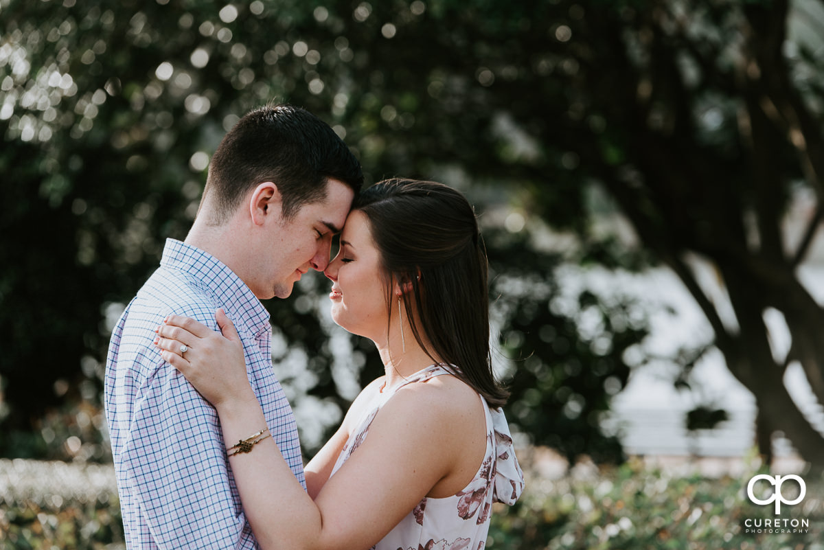 Engaged couple eskimo kissing in the rose garden at Furman University.