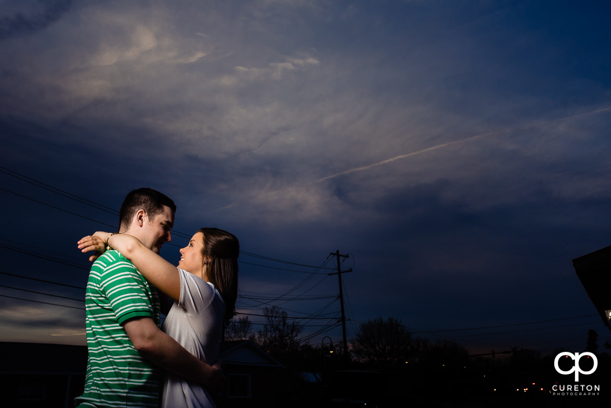 Bride and groom hugging underneath a purple sky.