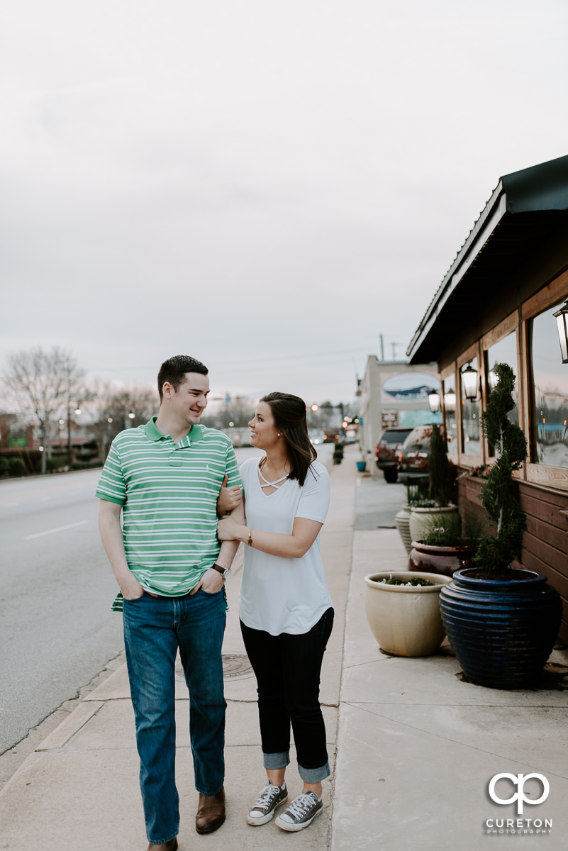 Engaged couple walking down the streets of downtown Travelers Rest during their Swamp Rabbit Brewery engagement session.