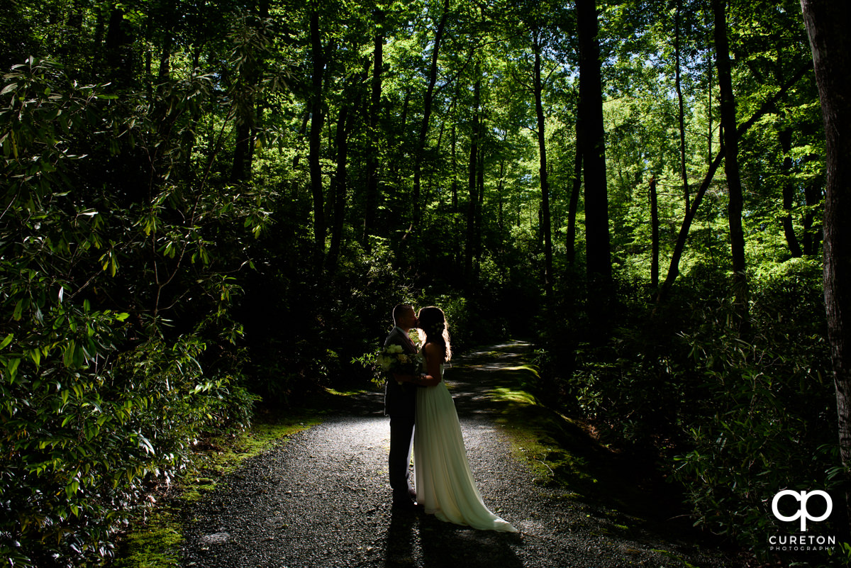 Bride and groom kissing in the forest after their mountain elopement wedding at Symmes Chapel.