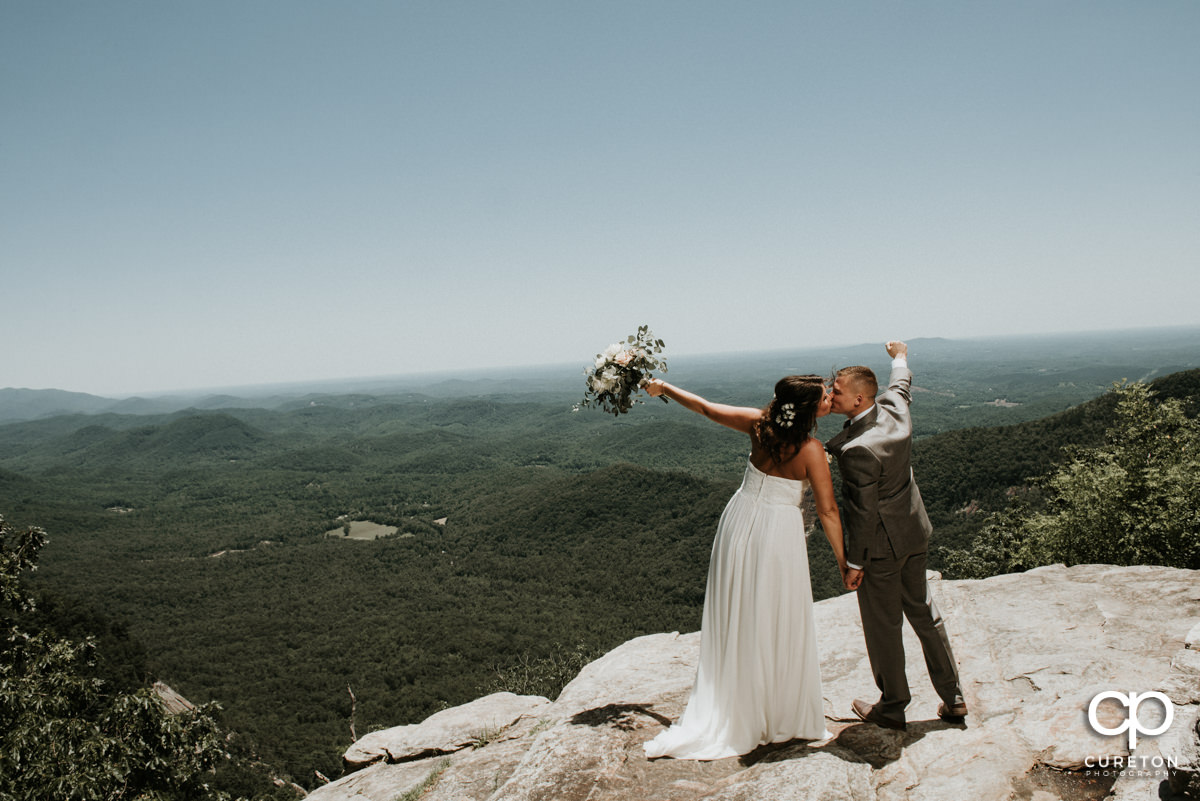 Bride and groom standing on a cliff at Pretty Place after their mountain elopement wedding at Symmes Chapel.