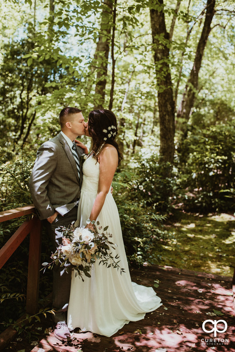 Bride and groom kissing in the forest after their mountain elopement.