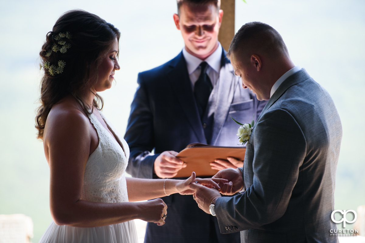Groom placing the ring on his bride's finger.