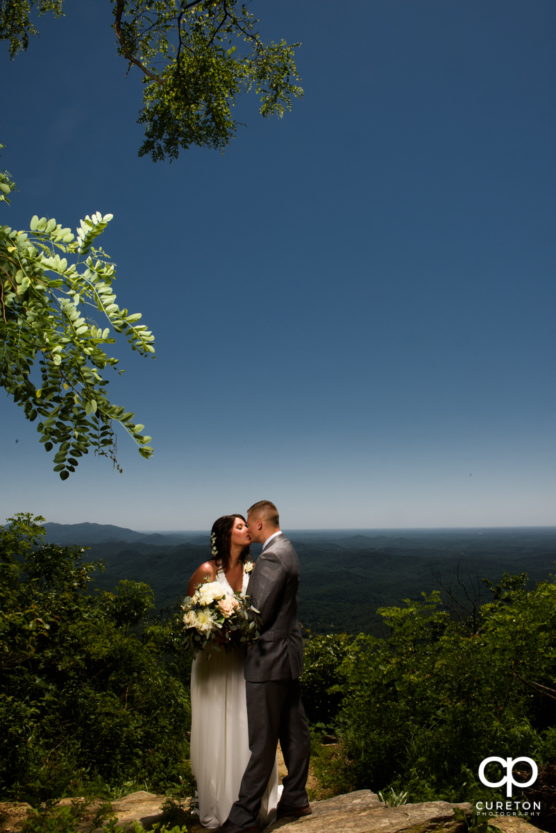 Groom kissing his bride on a mountainside after a Symmes Chapel wedding ceremony.