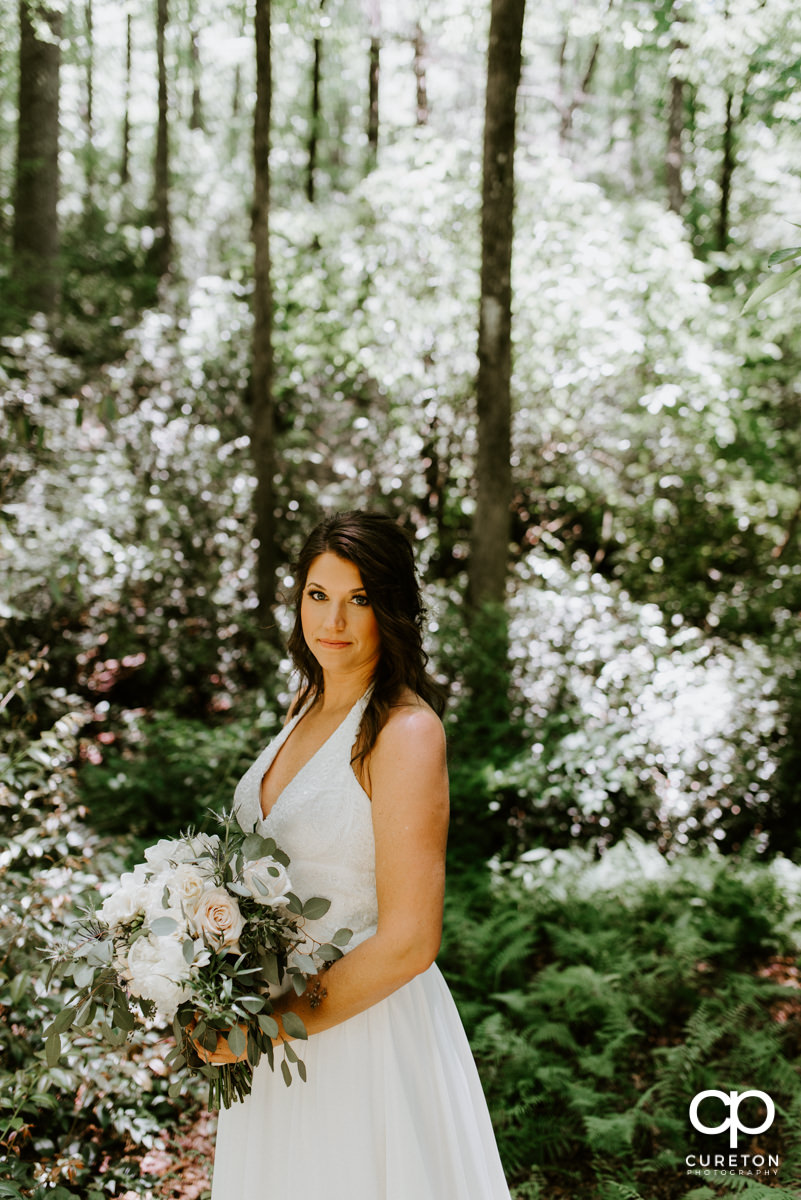 Bride in the forest holding her bouquet.