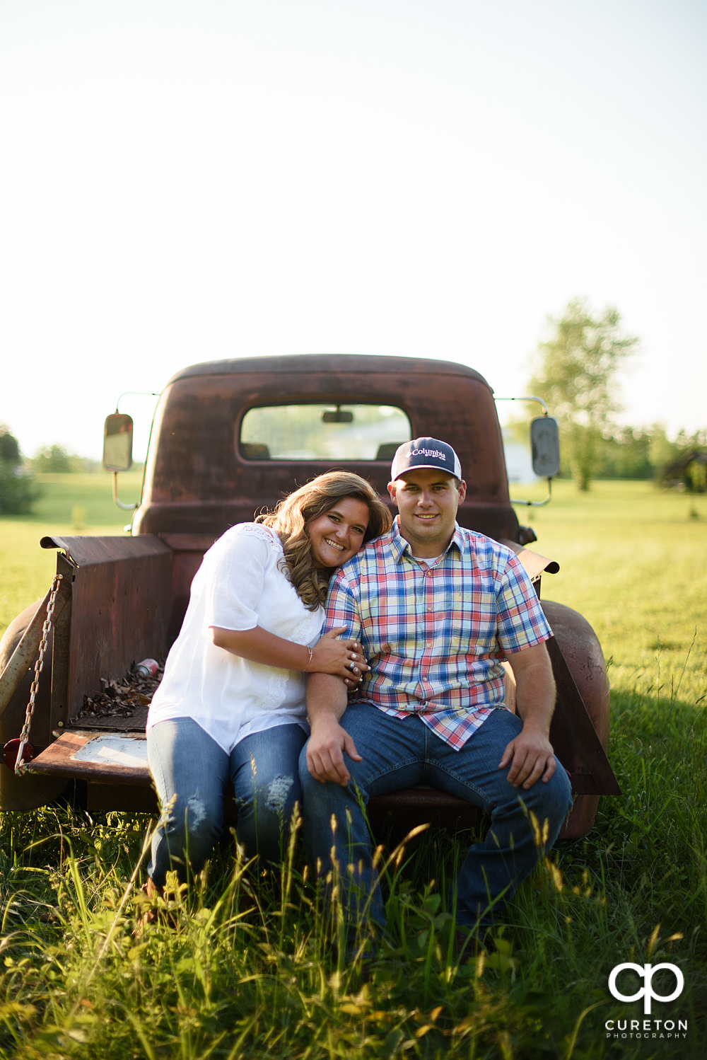Engaged couple sitting on the tailgate of a vintage truck during a Travelers Rest engagement session.