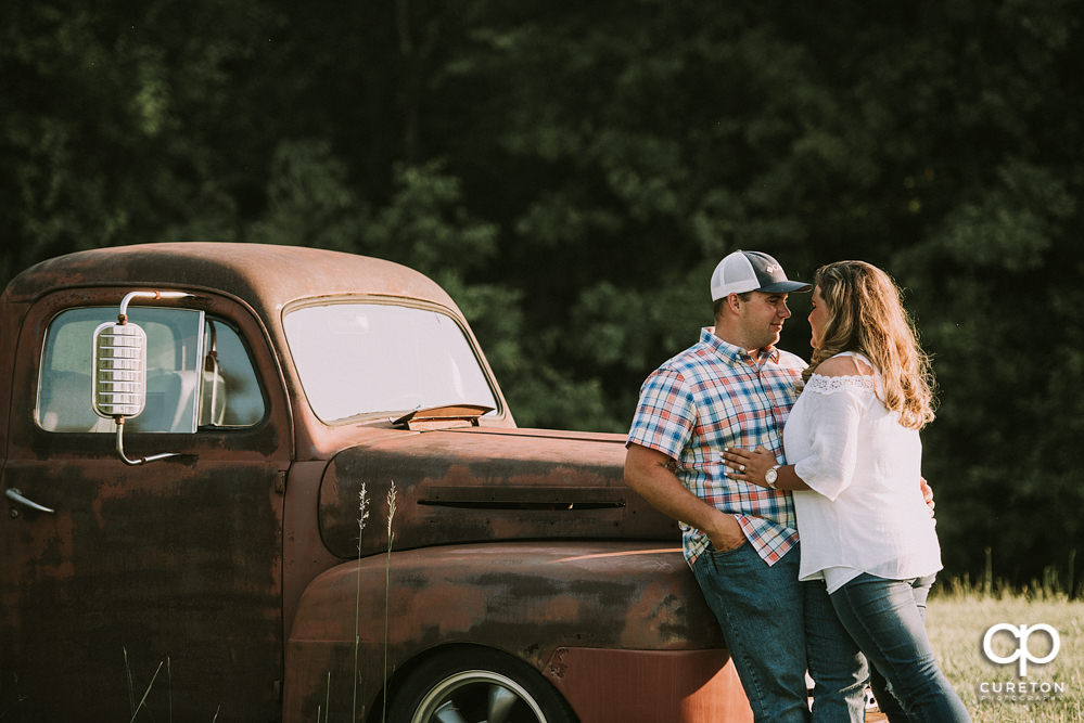 Bride and groom leaning on a truck.