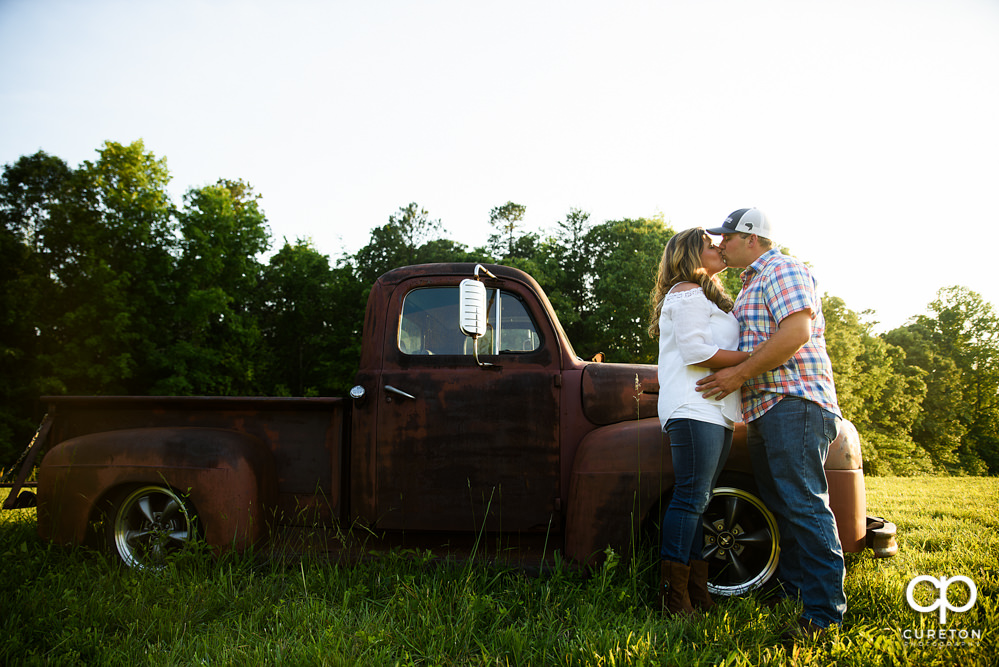 Engaged couple kissing near a truck during a Travelers Rest engagement session.