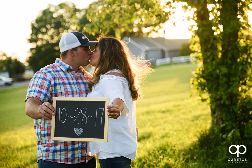 Engaged couple holding up a sign with their wedding date on it.